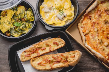 İtalyan makarna yemeğini al. Plastik kutu üzerinde kutu yeşil biber, sarımsak ekmek, fetuccine ve ravioli ile pizza.