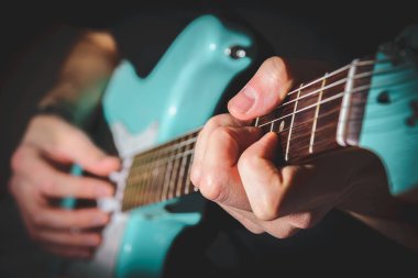 Mavi elektro gitar çalan adam evde yakın. Pratik gitar