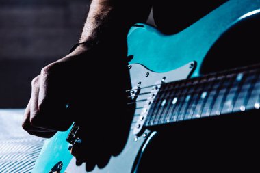 Mavi elektro gitar çalan adam evde yakın. Pratik gitar