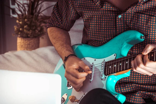 Mavi elektro gitar çalan adam evde yakın. Pratik gitar ve solo öğrenme gitar çalma