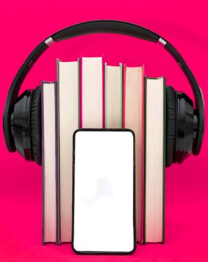 Sesli kitap konsepti. Kulaklıklar pembe mor arka plan üzerinde kitap koymak. Akıllı telefon