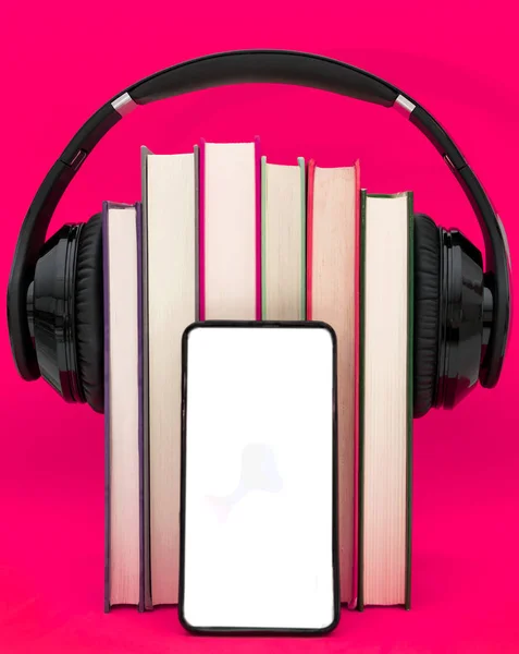Sesli kitap konsepti. Kulaklıklar pembe mor arka plan üzerinde kitap koymak. Akıllı telefon