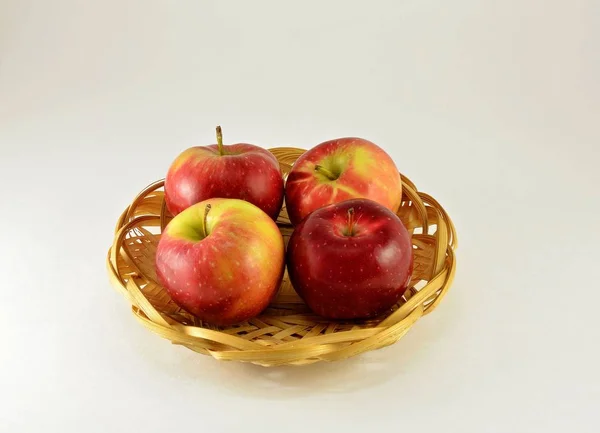 In the basket there are four large apples, juicy with red sides on a white background