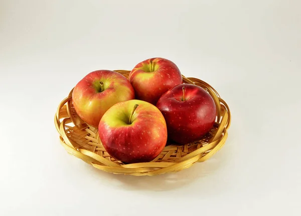 In the basket there are four large apples, juicy with red sides on a white background