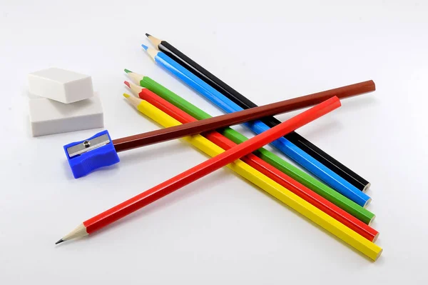 Set of colored pencils for drawing with erasers and sharpener on white background. — Stock Photo, Image