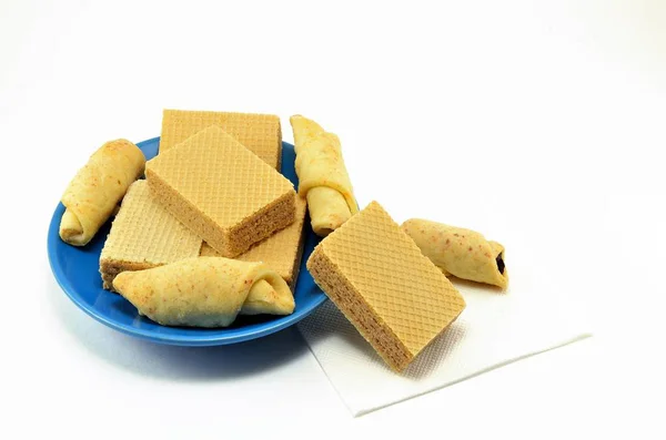Tatlı hamur işleri-rulo, çerezler ve waffle mavi bir plaka üzerinde beyaz bir arka plan üzerinde ateş.