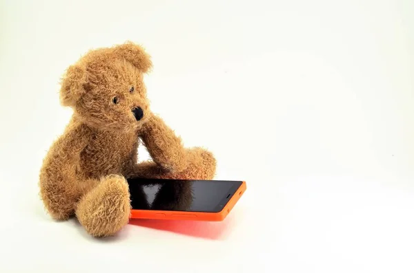 Kahverengi oyuncak ayı oyuncak ve cep telefonu turuncu gövdeli.