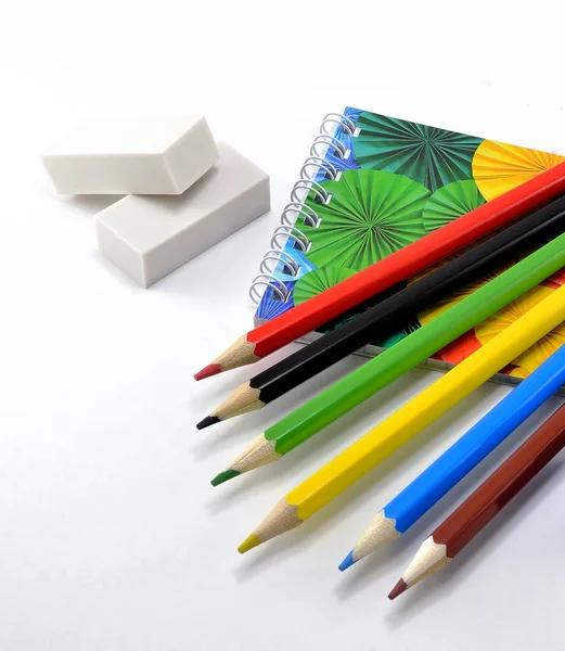 Renkli kalemler silgiler, kalemtıraş ve Not defteri ile beyaz arka plan üzerinde ayarla.