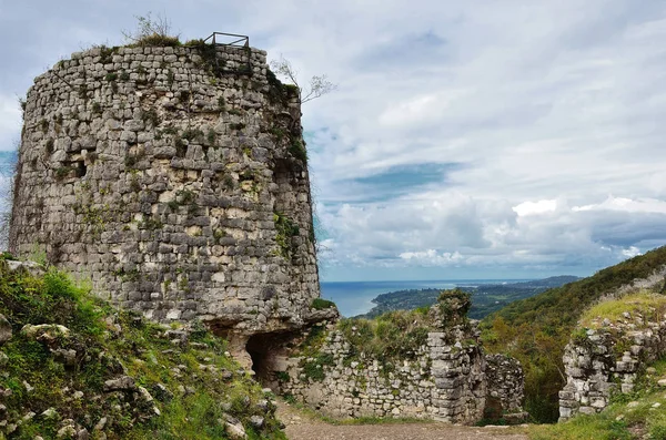 Mavi gökyüzünde bulutlar karşı dağlarda bir antik gözetleme kulesi kalıntıları.