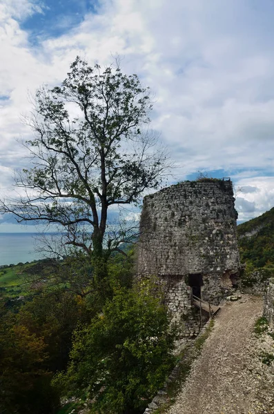 Mavi gökyüzünde bulutlar karşı dağlarda bir antik gözetleme kulesi kalıntıları.