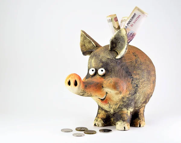 Clay piggy Bank with coins and paper money.