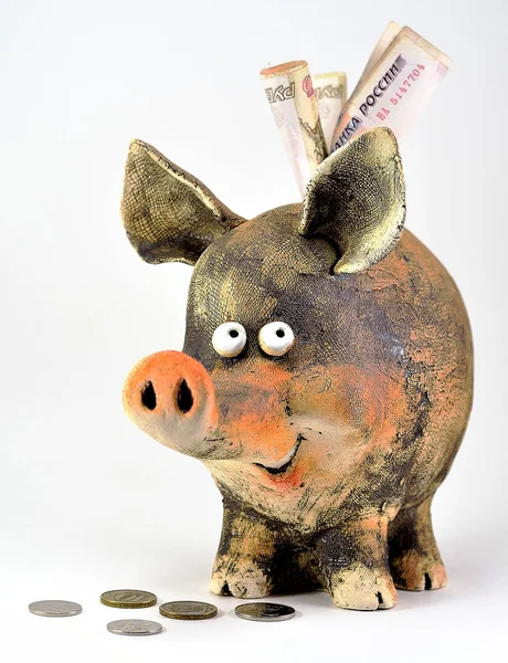 Clay piggy Bank with coins and paper money.