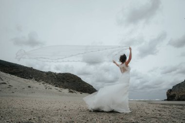 Gelin güzel rüzgarda gelişen peçe. Llooking denizde.