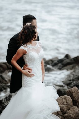 Gelin ve damat sahilde yürüyor. Panoramik görünümü. Sarılma.