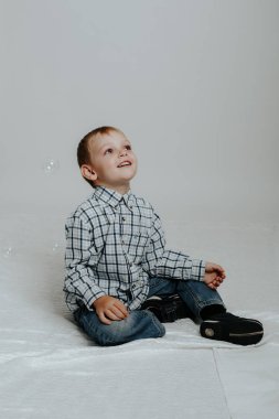 Küçük çocuk sabun köpüğüyle oynuyor.