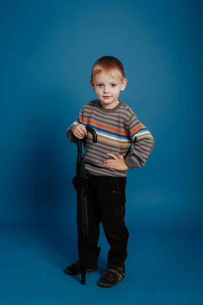 Un niño pequeño está de pie con un paraguas cerrado . —  Fotos de Stock