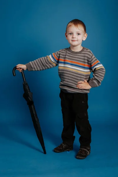 Un niño pequeño está de pie con un paraguas cerrado . —  Fotos de Stock