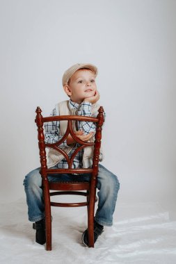 Bir kap içinde küçük bir çocuk bir sandalyeye oturur ve düşünüyor.