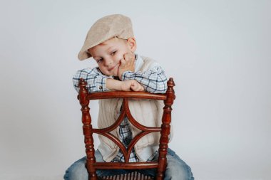 Bir kap içinde küçük bir çocuk bir sandalyeye oturur ve düşünüyor.