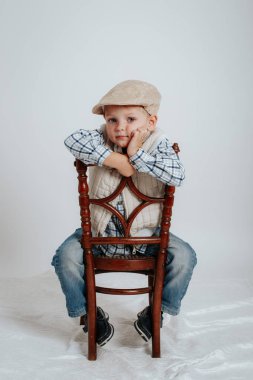 Bir kap içinde küçük bir çocuk bir sandalyeye oturur ve düşünüyor.