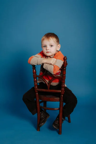Egy kisfiú, egy sapkát leül egy székre, és úgy gondolja. — Stock Fotó