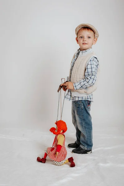 Маленький хлопчик в шапці стоїть з лялькою — стокове фото