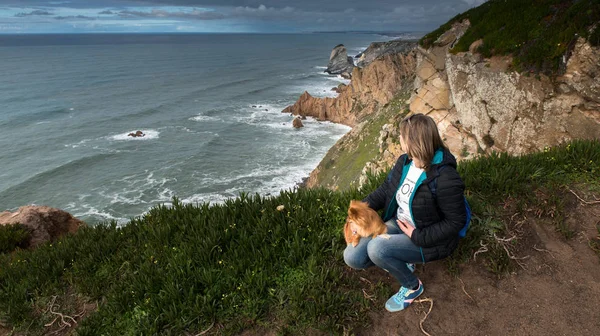 Kadın, Atlas Okyanusu kıyısında oturan bir köpek ile kız