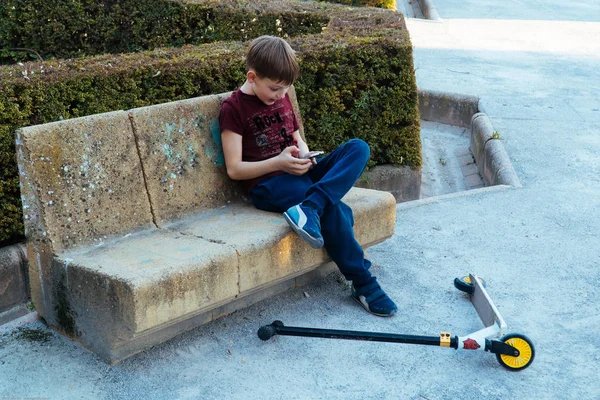 Nowoczesne problemy dzieci. Dziecko bawi się telefonem w parku.. — Zdjęcie stockowe