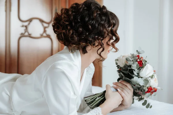 Sposa con un mazzo di fiori nuziali sdraiato sul letto — Foto Stock