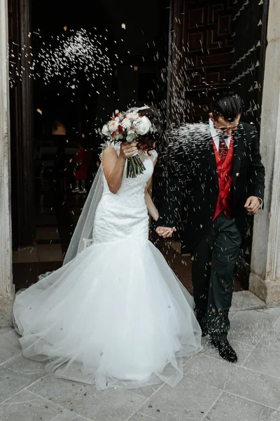People throw rice on newlyweds walking out of the church — Stock Photo, Image