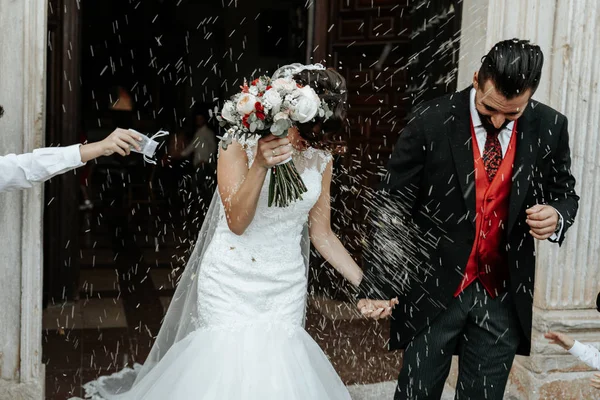 Orang-orang melemparkan beras pada pengantin baru berjalan keluar dari gereja — Stok Foto