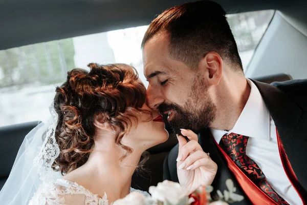 Glückliches romantisches Brautpaar küsst sich in Hochzeitslimousine - — Stockfoto