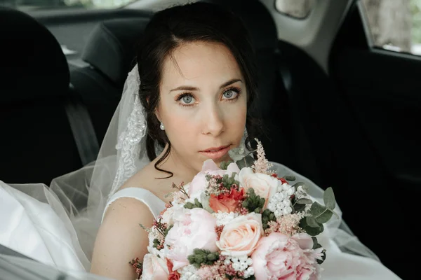 Düğün buketi ile bir araba penceresinde güzel bir gelinin yakın çekim portresi — Stok fotoğraf