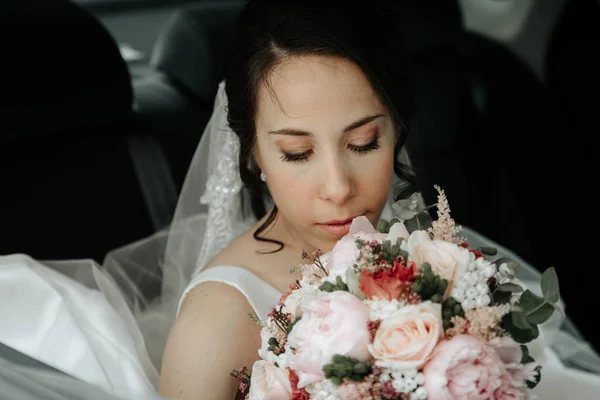 Gelin bir buket ile düğün gününde araba penceresinde oturur. — Stok fotoğraf