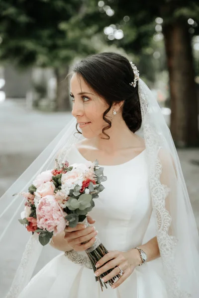 Sorridente bella giovane sposa in abito da sposa con mazzo di fiori — Foto Stock