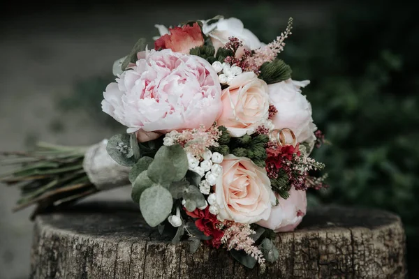 Свадебный букет из роз с кольцами на деревянной скамейке — стоковое фото