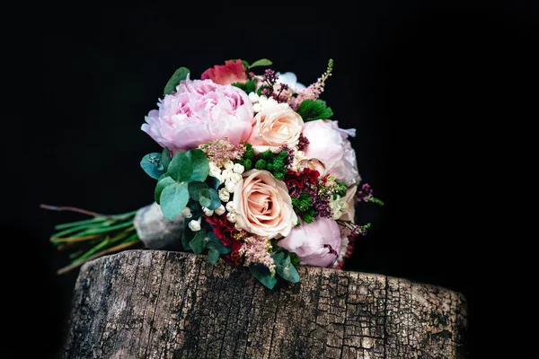 Wedding bouquet of roses with rings on wooden bench