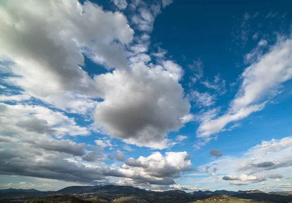 Bílé mraky na modré obloze nad horami. — Stock fotografie