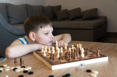 Satranç oynayan çocuk. Ciddi çocuk satranç oynarken düşüncelere daldı. Coronavirus karantinasında masa oyunu oynuyoruz..