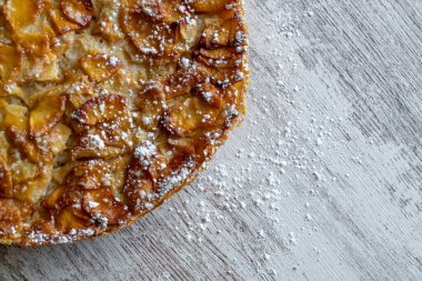 Hafif ahşap arka planda taze pişmiş elmalı turta üzerine krema serpiştirilmiş şeker. Ev yapımı pişirme..