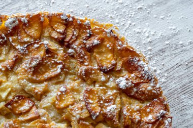 Hafif ahşap arka planda taze pişmiş elmalı turta üzerine krema serpiştirilmiş şeker. Ev yapımı pişirme..