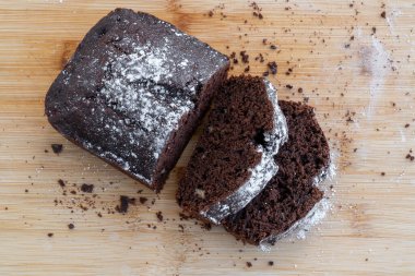 Tahta bir masada ev yapımı çikolatalı pasta dilimlenmiş. Ev yapımı hamur işi tarifi.