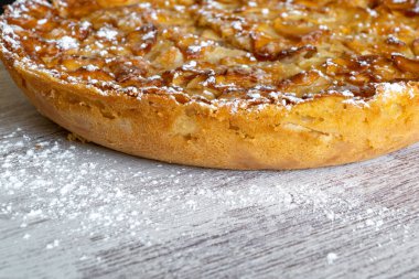 Ev yapımı pişirme. Hafif ahşap arka planda taze pişmiş elmalı turta üzerine şekerleme serpiştirilmiş..