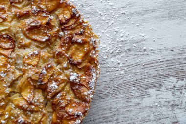 Ev yapımı pişirme. Hafif ahşap arka planda taze pişmiş elmalı turta üzerine şekerleme serpiştirilmiş..