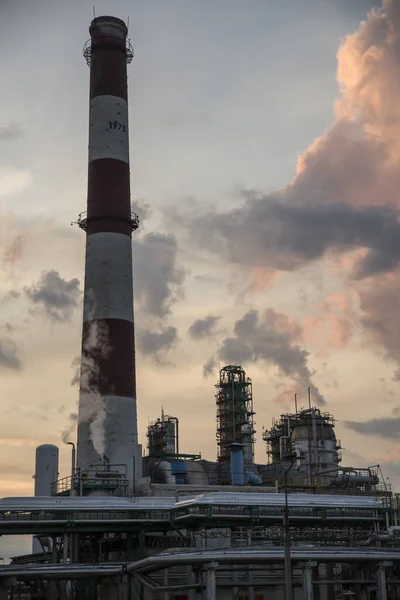 Bulutlu gökyüzü olan bir petrokimya fabrikasının rafineri kulesi. Gün batımından sonra