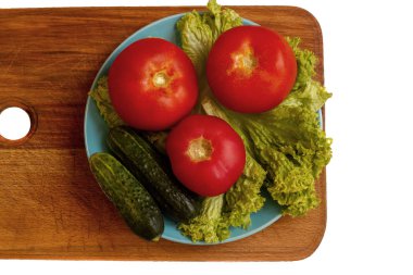 ahşap kesme tahtası üzerinde üç domates, iki salatalık ve salata yaz karışımı