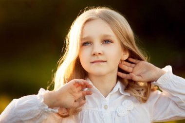 Yaz aylarında gün batımında kulaklı bir alandaki beyaz elbiseli güzel bir kız portresi. Yakın çekim