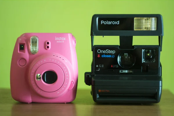 two instant print cameras - Polaroid One Step and Fujifilm InstaxMini9 on a light green background
