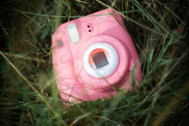 Pembe Instax Mini 9 kamera. Çimenlerdeki lenslerde gradyan filtre var.