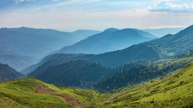 Yeşil dağ Vadisi konut binalar yüksek dağlarla çevrili yüksekliğini görünümden. Karla kaplı dağ zirveleri ufukta.